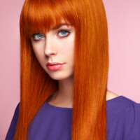 Portrait of beautiful woman with red hair. Colored long haircut. Perfect make-up. Girl in elegant violet dress. Red wig. Fashion photo